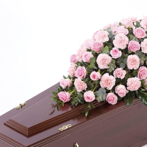 Large-headed roses combine with carnations and luxurious foliages to create this traditional casket spray.